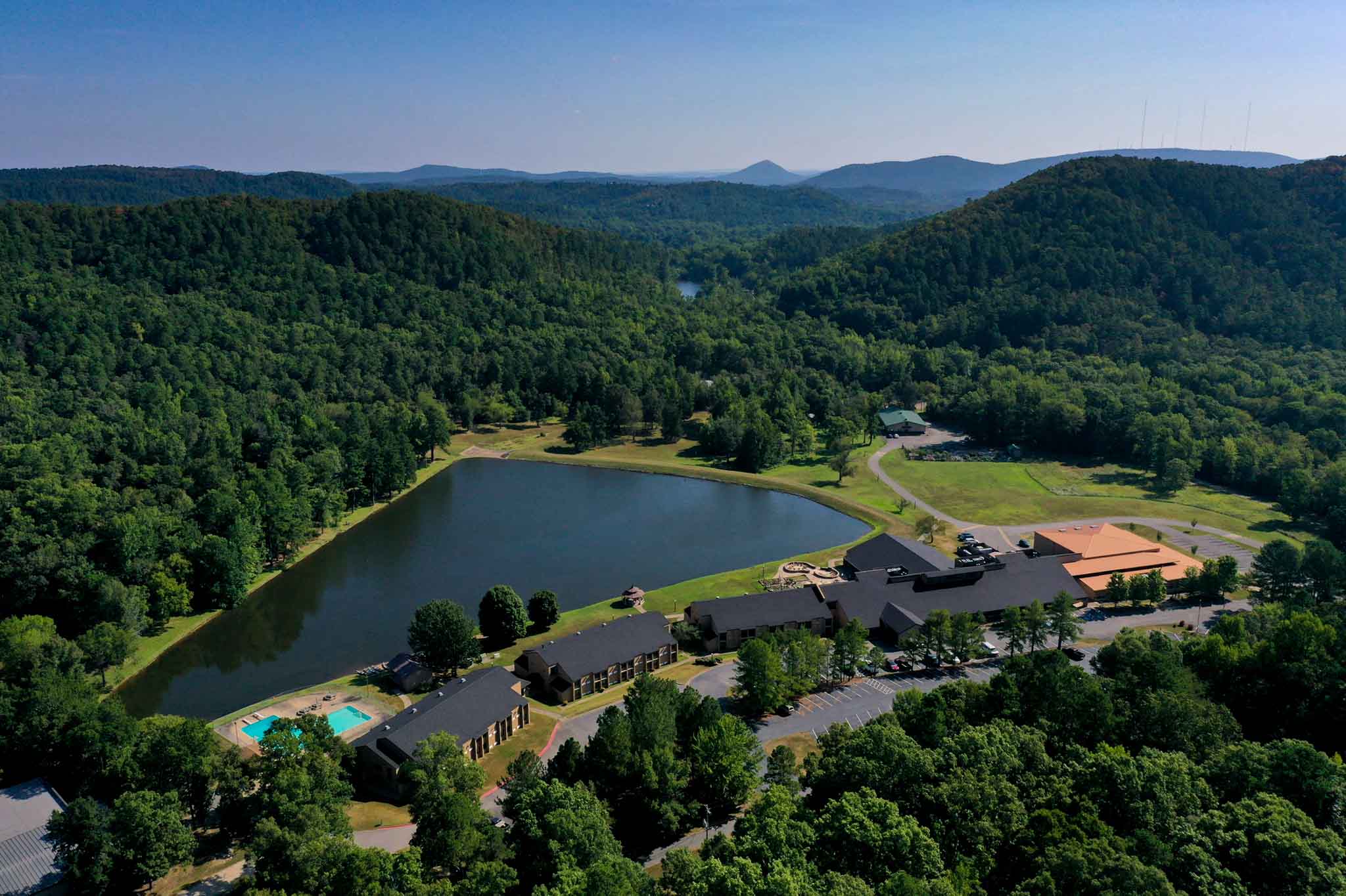 4H Vines Center Aerial view of The Vines Center: several buildings on the edge of a pond in the mountains.