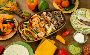 Fajitas with peppers, taco shells, and toppings on a table